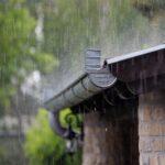 Starker Regen läuft von einem Hausdach in die Regenrinne – Symbolbild für Regenwassernutzung der zisterne