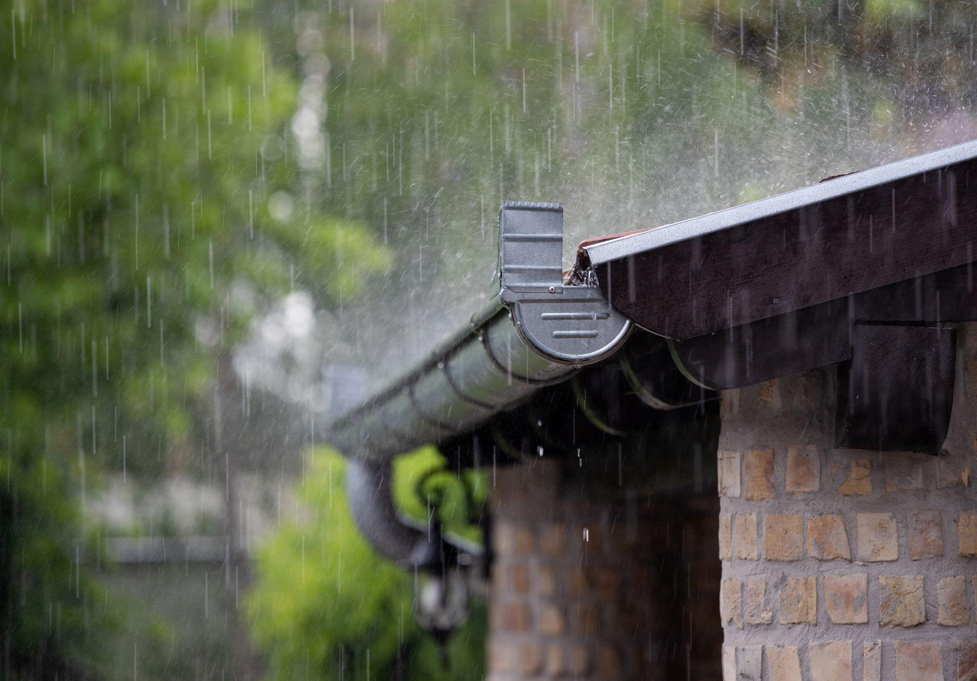 Starker Regen läuft von einem Hausdach in die Regenrinne – Symbolbild für Regenwassernutzung der zisterne