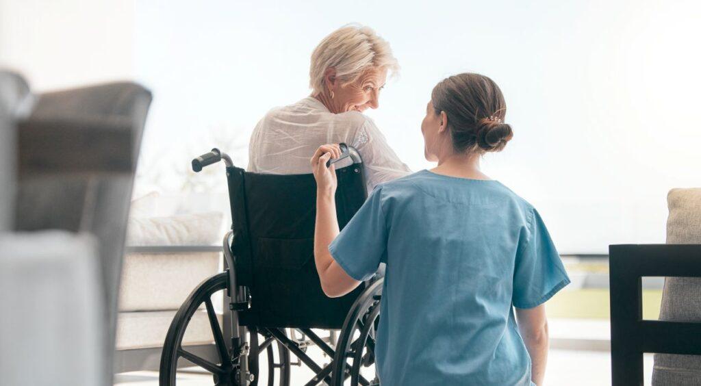 Pflegekraft begleitet Seniorin im Rollstuhl bei Tageslicht – Pflegedienst Ahlen im ambulanten Einsatz