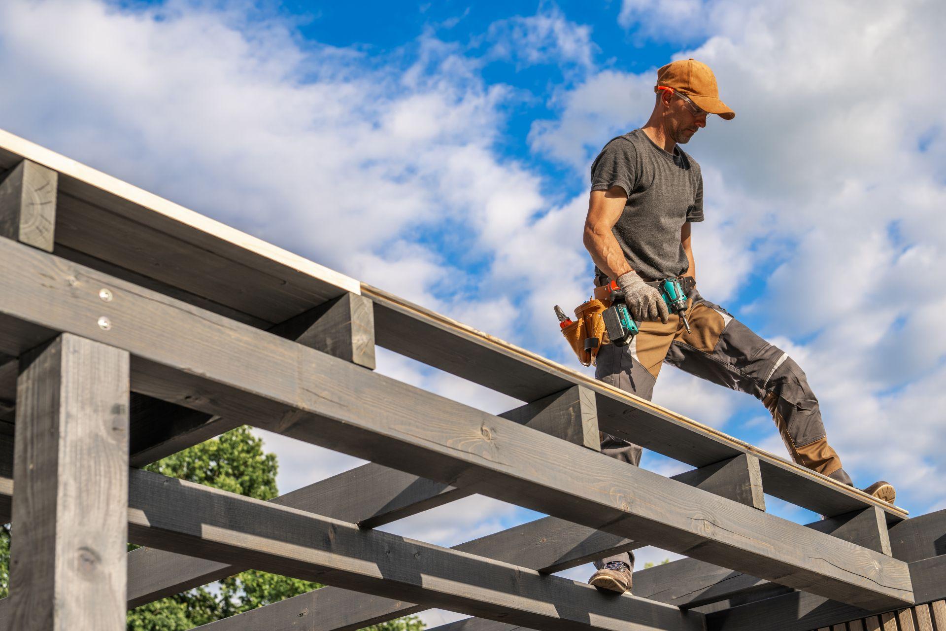Handwerker montiert individuelle Terrassenüberdachung aus Holz bei klarem Himmel – Detailbild des Bauprozesses
