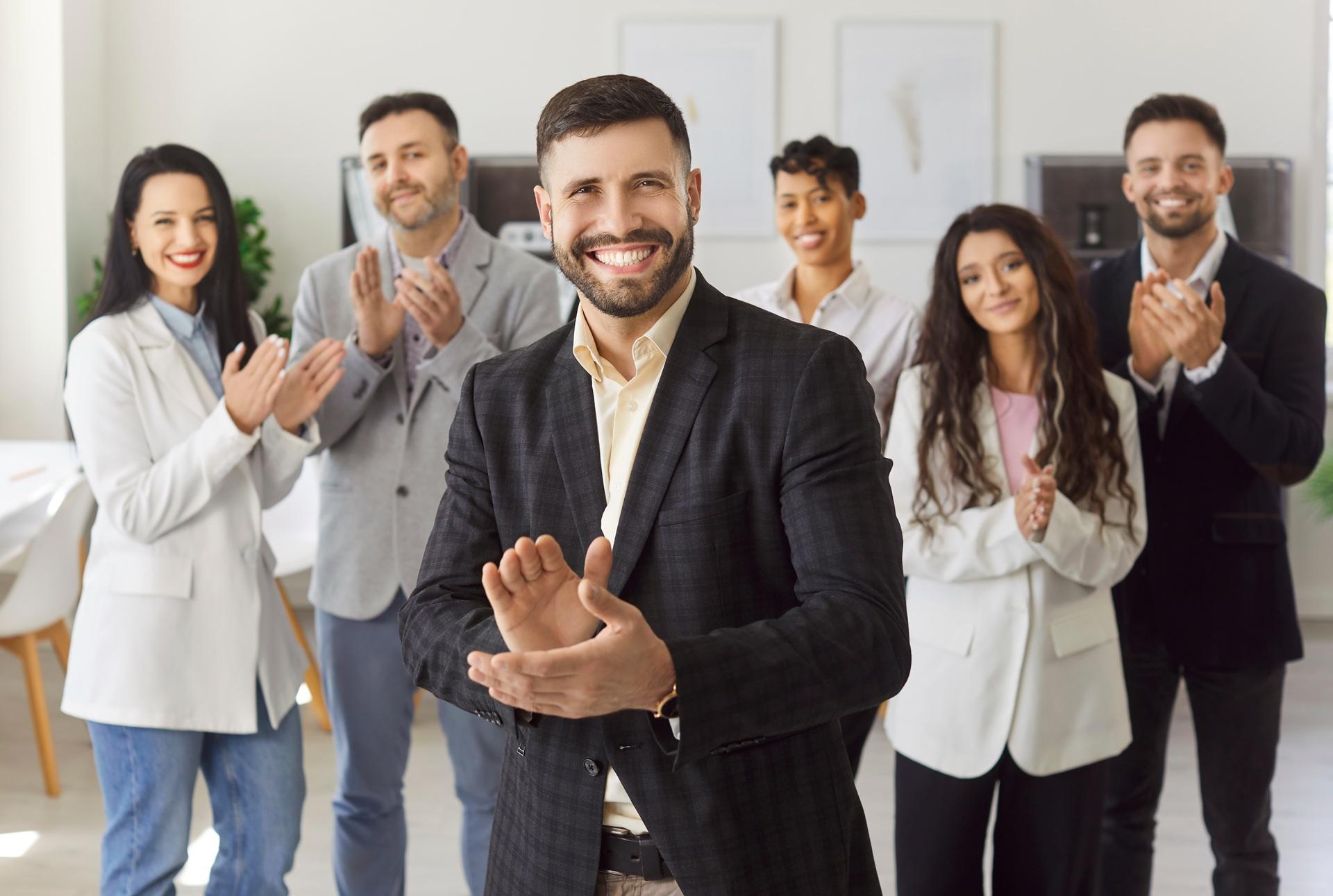 Team applaudiert lächelndem Kollegen im Büro | betriebliche Gesundheitsförderung